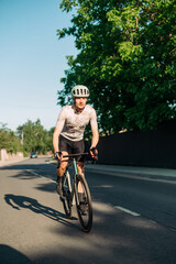 Fototapeta premium A male cyclist in sports equipment is riding fast outside the city on the road on a road bike. Vertical photo.