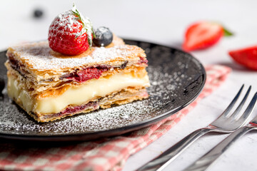 A piece of Napoleon cake with poppy seeds and cherries