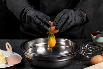 Cracking raw eggs into a bowl for making a cake