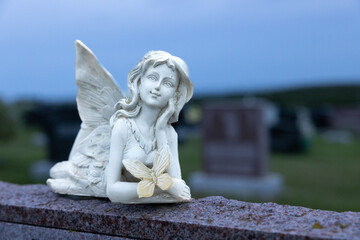 Ange pensif avec papillon sur pierre tombale