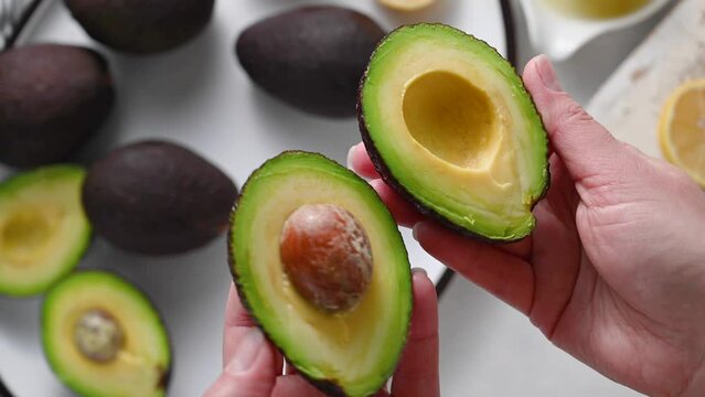 Fresh avocado. Woman holding half of fresh ripe avocado, top view