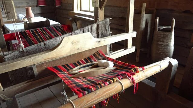 Ancient loom inside an old hut, a knitting and spinning machine. An old manufactory for the production of belts, towels and clothes