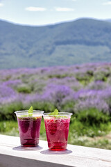 Two glasses of cool rose and lavender lemonades. Refreshing drinks with mint leaves. Rest in the lavender field field in the mountains. Antistress, restoration of mental health.