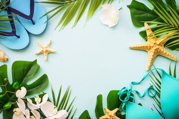 Summer flat lay background. Palm leaves, hat, flip flop and shells on blue. Summer composition with...