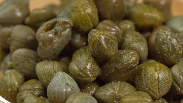 Pickled marinated capers rotate in macro. Ingredients for making spicy sauce, tartare or salad