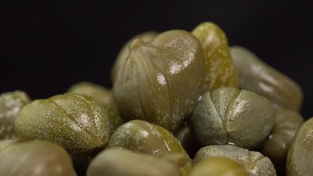 Pickled marinated capers rotate on a black background. Ingredients for making spicy sauce, tartare or salad