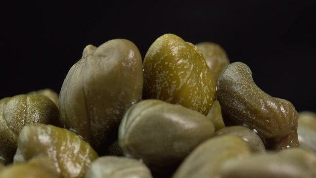 Pickled marinated capers rotate in macro on black background. Ingredients for making spicy sauce, tartare or salad