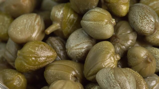 Pickled marinated capers rotate in macro. Ingredients for making spicy sauce, tartare or salad