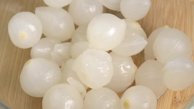 Hand takes pickled marinated mini pearl onion from glass bowl. Ingredients for cooking, snack for meat