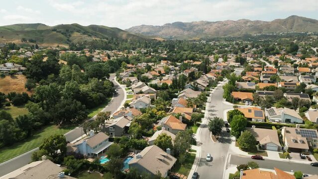Aerial view of typical suburban area in Los Angeles, Califonia, USA. Wealthy villas with swimming pools. Hills and mountains. Drone flyover of residential houses in sunny day. High quality 4k footage