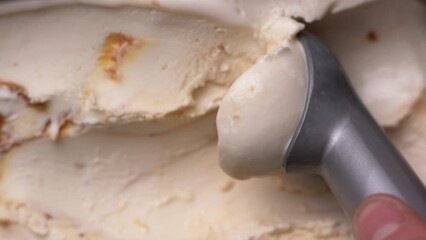 Toffee ice cream, flat lay. Top view. Spoon for ice cream takes a little out of the container and making a cream ball