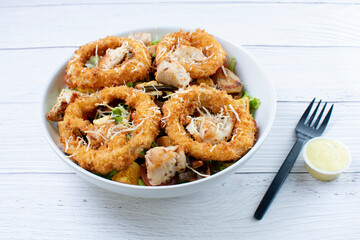 Bowl salad with pieces of roast pork, grated cheese, onion rings and house mayonnaise