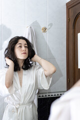 Latin woman in bathroom. Young female playing with her hair in front of a mirror.