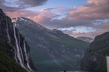 Naklejka premium Dramatic colorful twilight summer sunset on the Geiranger fjord in Norway with vibrant clouds steep cliffs and waterfalls
