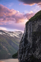 Dramatic colorful twilight summer sunset on the Geiranger fjord in Norway with vibrant clouds steep cliffs and waterfalls