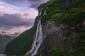 Dramatic colorful twilight summer sunset on the Geiranger fjord in Norway with vibrant clouds steep cliffs and waterfalls