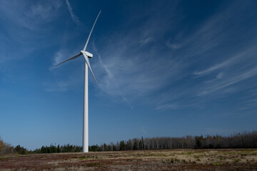 White windmill in the fields, with blue sky. Eolian Energy.