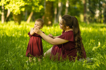 Fototapeta premium Embracing happiness: A mother and her one-year-old girl enjoying a sunny day at the park, smiles on their faces as they share a loving hug