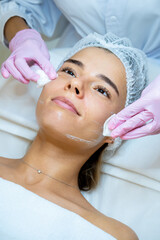 Beautician doctor cleaning woman face with cotton pads, skin care procedures, rejuvenation.