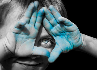Garçon aux yeux bleu avec des mains coloriées en bleu en selective couleur