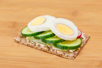 Whole Grain Crispbread with Fresh Cucumber, Egg, Cream Cheese and Radish on Bamboo Cutting Board. Easy Breakfast. Quick and Healthy Sandwiches. Crispbread with Tasty Filling. Healthy Dietary Snack