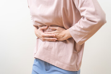 Flatulence asian young woman intolerance hand in stomach ache, suffer from food poisoning, abdominal pain and colon problem, gastritis or diarrhoea when at home. Patient belly, abdomen or inflammation