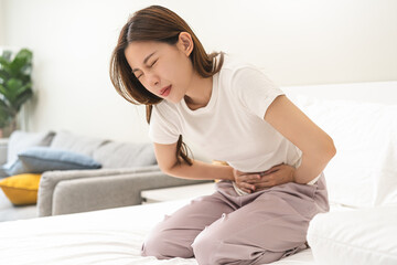 Naklejka premium Flatulence ulcer, asian young woman, girl hands in belly, stomach pain from food poisoning, abdominal pain and digestive problem, gastritis or diarrhoea. Abdomen inflammation, menstrual period people.
