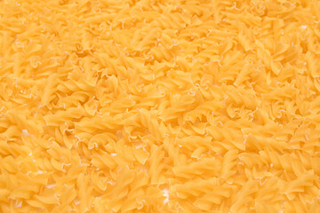 Uncooed Fusilli Pasta - Background. Texture of Bright Golden Dry Macaroni