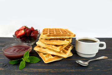 Square Belgian waffles with berries on a wooden background.
