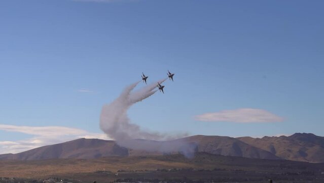 Fighter jets flying in formation with smoke mountains in the background