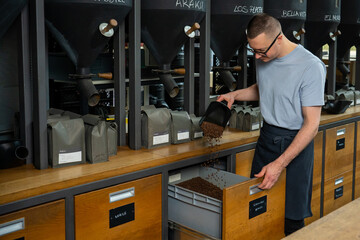 Caucasian coffeemaker working in roasting coffee shop.