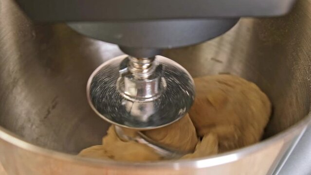 Adding ingredients to the metal bowl of the planetary mixer and mixing. Water, oil, yeast, salt, flour. Preparation of yeast dough for pizza.