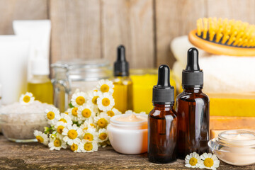 Chamomile Spa. Essential oil, sea salt, chamomile flowers, body cream and handmade soap. Natural herbal cosmetics with chamomile flowers on a textured background.Beauty concept. Cosmetic tube. 