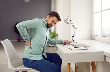 Exhausted man feeling pain in back suffering from lower lumbar backache. Unhappy businessman...
