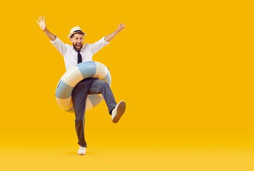 Funny office worker on summer holiday. Happy, funny, excited man in white shirt, tie, trousers, sun hat and beach ring walking isolated on empty yellow copy space background, looking away and smiling