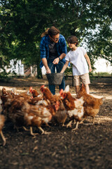 Farther and son feeding their chickens.
