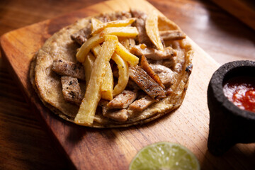 Beef steak taco with french fries. Very popular taco in Mexico called Taco de Bistec or Carne Asada, homemade roast beef served on a corn tortilla. Mexican street food.