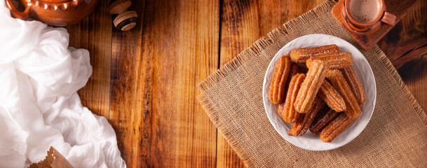 Fototapeta na wymiar Churros. Fried wheat flour dough, a very popular sweet snack in Spain, Mexico and other countries. It is customary to eat them for breakfast or snack accompanied by hot chocolate . Table topview