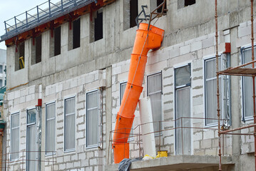 Building construction and debris chute on facade of new building, disposal of construction waste...