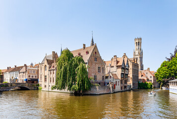 Fototapeta na wymiar The Quay of the Rosary (Rozenhoedkaai) canal in Bruges with the classic medieval buildings and the Belfry Tower of Bruges in the background, Belgium