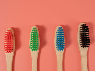 Bamboo toothbrushes in different colors. Wooden toothbrush on a pink background. Toothbrush close-up.