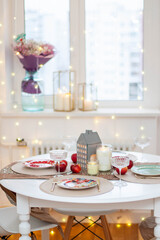 Christmas table setting with burning candles, retro lights and champagne glasses. Warm and cozy atmosphere