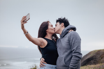 Photograph of a young couple taking a selfie with their cell phone. Lifestyle concept, convenience and couples.
