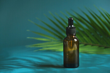 Drop of clear liquid, oil, serum or tincture dripping from pipette in the neck of a brown medical...