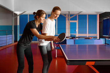 Adult woman instructor teaching female student play table tennis