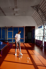 Woman picking balls after training class at ping pong sport club