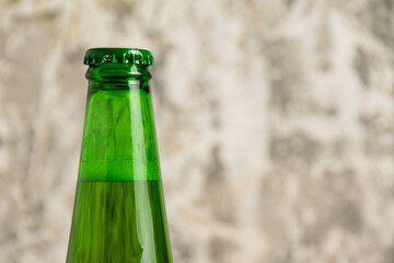 Aromatic beer in glass bottle on gray concrete background with copy space
