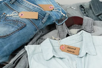 Photo sur Plexiglas Vielles portes Stack of blue jeans, shirts and tag with inscription second hand. Second hand clothing shop. Circular fashion, eco friendly sustainable shopping, thrift stores concept. Top view over woman outfit