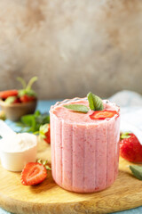 Fresh milk, strawberry drinks on wooden board on a stone background, protein shake with fresh berries. Copy space.