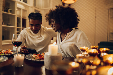 African american couple having romantic date and using smartphone at home